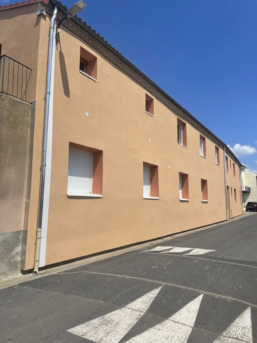 Long bâtiment à façade enduite orange après ravalement